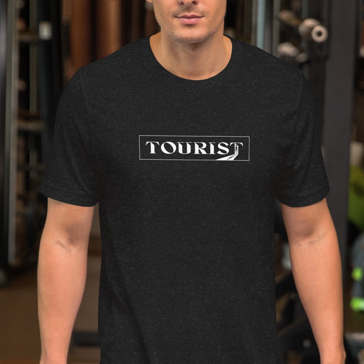 Dark gray color heather tee with the word Tourist in a rectangle with an alien on a model