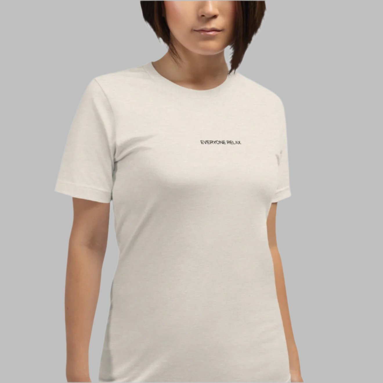 Heather dust color tee with the small words Everyone Relax on a female model