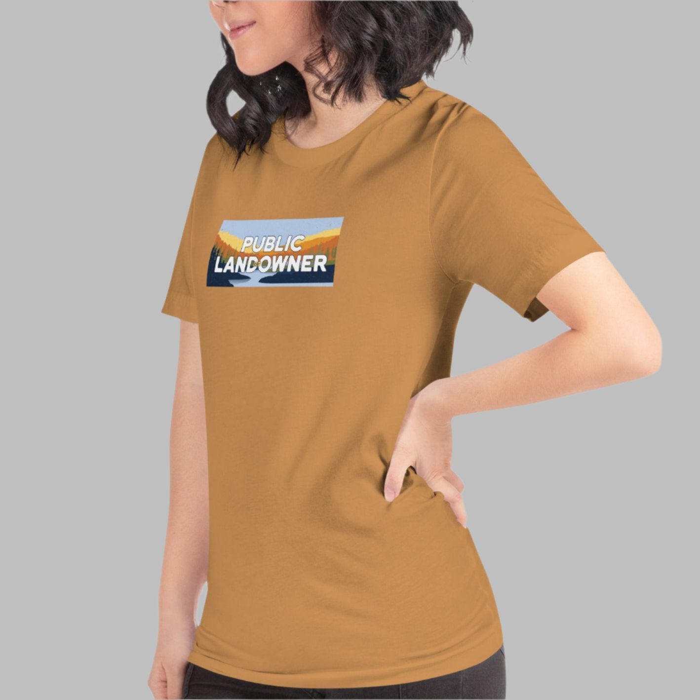 toast color heather tee with a rectangle landscape saying Public land co-owner inside on female model